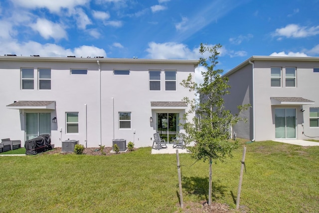 rear view of house featuring stucco siding, central AC, a yard, and a patio area