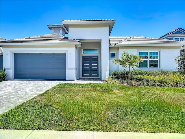 view of front of property featuring a tiled roof, a garage, decorative driveway, and stucco siding