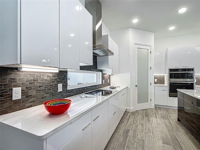 kitchen with modern cabinets, black electric stovetop, stainless steel double oven, decorative backsplash, and white cabinetry