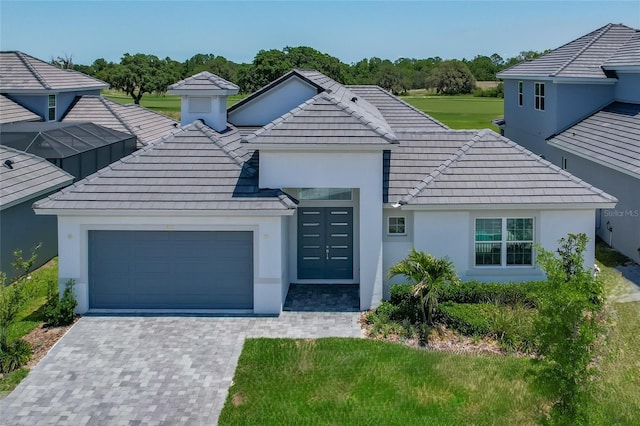 view of front of property featuring a garage, a tile roof, and stucco siding