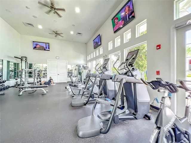 workout area with a towering ceiling, ceiling fan, and plenty of natural light