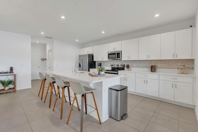 374 Pine Tree Bridge Trl, Saint Cloud, FL 34772 - kitchen featuring stainless steel appliances, tasteful backsplash, recessed lighting, light tile patterned flooring, and a center island with sink
