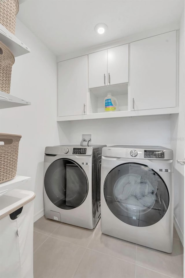 374 Pine Tree Bridge Trl, Saint Cloud, FL 34772 - clothes washing area featuring washer and dryer, light tile patterned floors, cabinet space, and baseboards