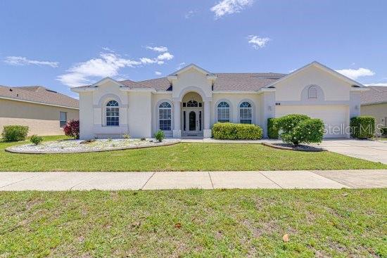 mediterranean / spanish home featuring driveway, a garage, a front yard, and stucco siding