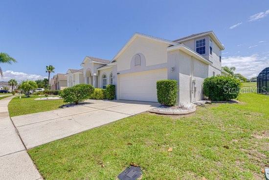 view of front of house featuring concrete driveway, a front lawn, a garage, and stucco siding