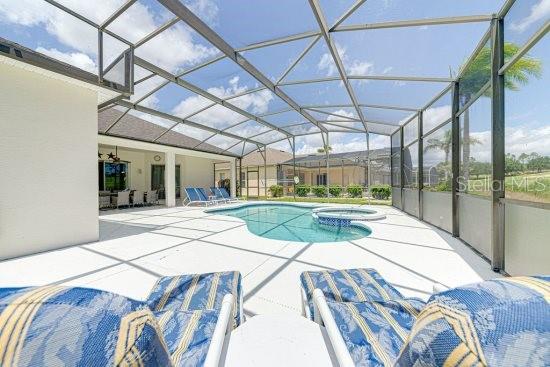 view of pool featuring a patio, a pool with connected hot tub, and glass enclosure