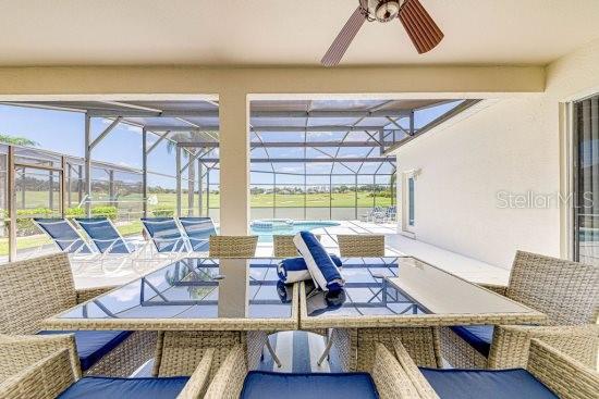 view of patio featuring ceiling fan, outdoor dining space, an outdoor pool, and a lanai