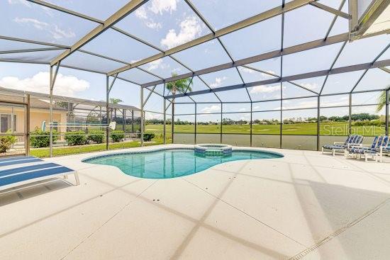 view of swimming pool with a pool with connected hot tub, a patio area, and a lanai