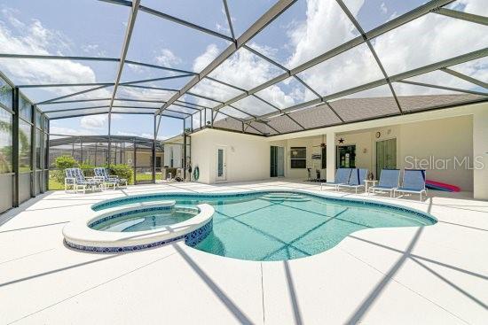 view of pool featuring a patio area, a pool with connected hot tub, and glass enclosure