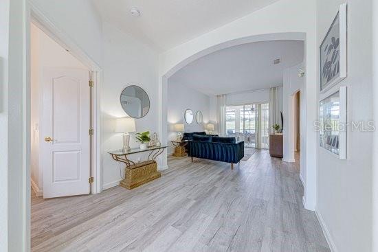 hall featuring arched walkways, wood finished floors, and baseboards