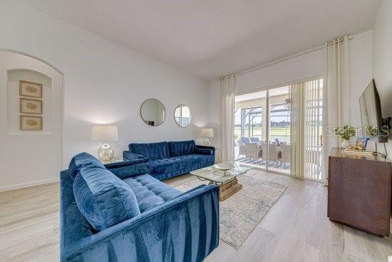 living room featuring wood finished floors, arched walkways, and baseboards