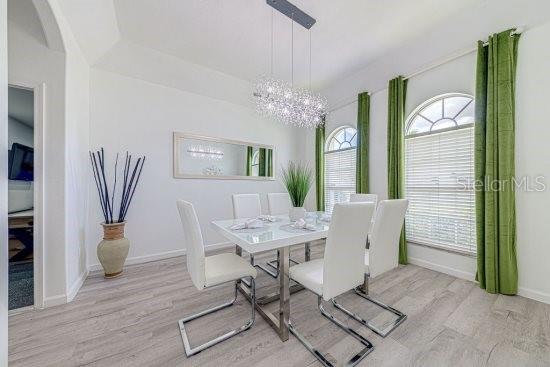 dining space featuring a chandelier, wood finished floors, baseboards, and healthy amount of natural light