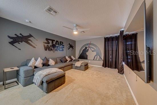 carpeted living room featuring baseboards, a textured ceiling, and ceiling fan