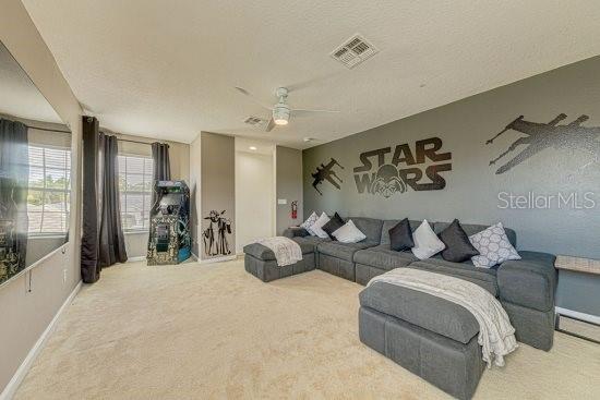 carpeted living area with baseboards and ceiling fan