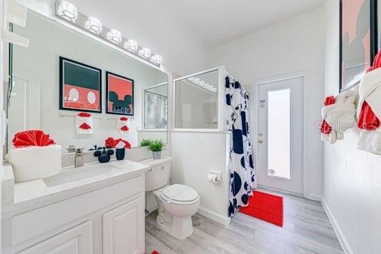 full bathroom with wood finished floors, a shower stall, toilet, and vanity