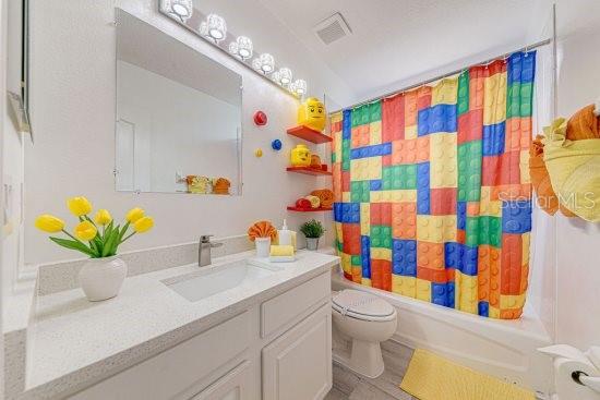 bathroom with toilet, shower / tub combo, and vanity