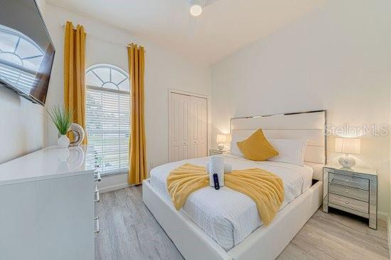 bedroom with wood finished floors, multiple windows, and a closet