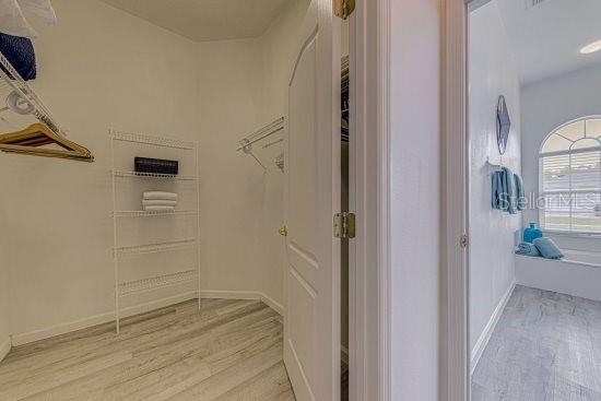 walk in closet with light wood finished floors