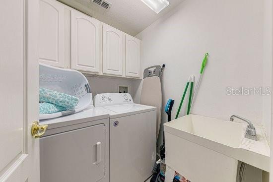 laundry room with washing machine and clothes dryer and cabinet space