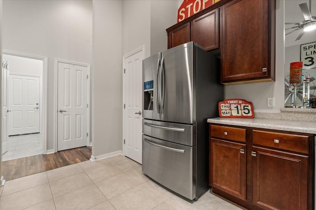 kitchen with stainless steel fridge, a high ceiling, light countertops, light tile patterned flooring, and ceiling fan