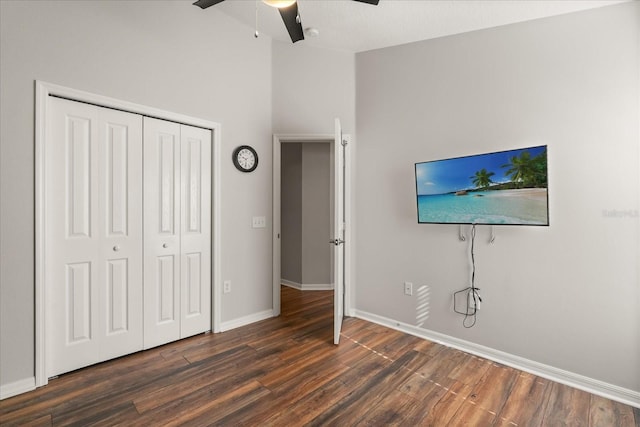 unfurnished bedroom featuring dark wood-style floors, baseboards, a closet, high vaulted ceiling, and a ceiling fan