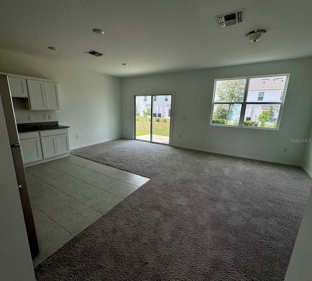 unfurnished living room with light colored carpet and baseboards