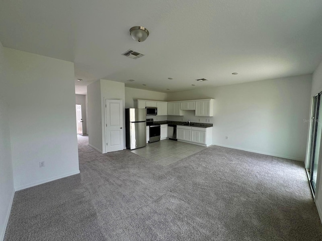 unfurnished living room with carpet, baseboards, and a sink