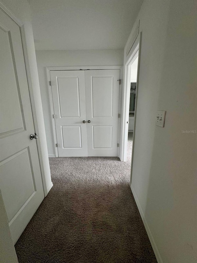 hall featuring carpet and baseboards