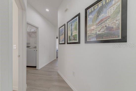 2908 Sunset Lakes Blvd, Kissimmee, FL 34747 - hallway with washer and clothes dryer, light wood finished floors, recessed lighting, and baseboards