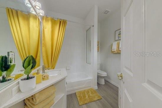 2908 Sunset Lakes Blvd, Kissimmee, FL 34747 - bathroom featuring toilet, wood finished floors, vanity, and tub / shower combination