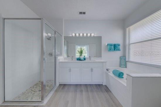 2908 Sunset Lakes Blvd, Kissimmee, FL 34747 - full bathroom with wood finished floors, a shower stall, a bath, and double vanity