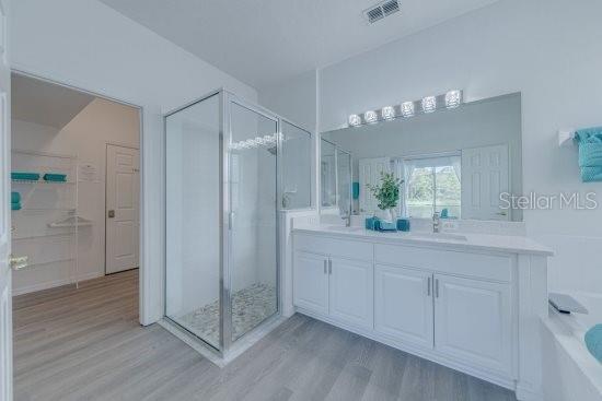 2908 Sunset Lakes Blvd, Kissimmee, FL 34747 - full bathroom with wood finished floors, a shower stall, double vanity, and a garden tub