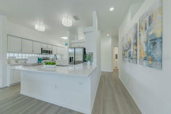 2908 Sunset Lakes Blvd, Kissimmee, FL 34747 - kitchen featuring stainless steel appliances, light wood-style floors, light countertops, white cabinets, and recessed lighting