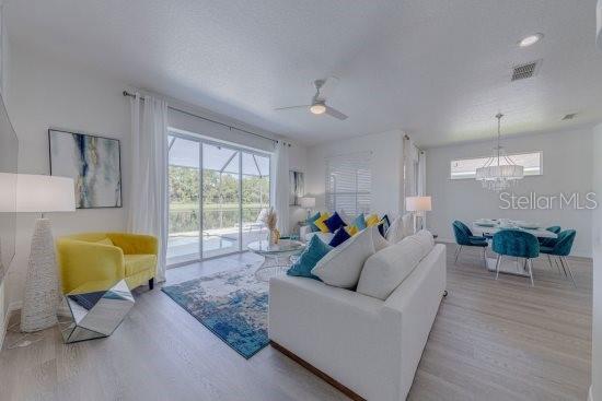 2908 Sunset Lakes Blvd, Kissimmee, FL 34747 - living room with wood finished floors, a ceiling fan, and a chandelier