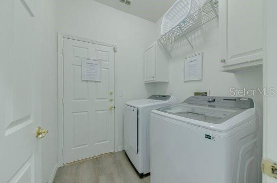 2908 Sunset Lakes Blvd, Kissimmee, FL 34747 - laundry area with washing machine and dryer, cabinet space, and light wood-style flooring