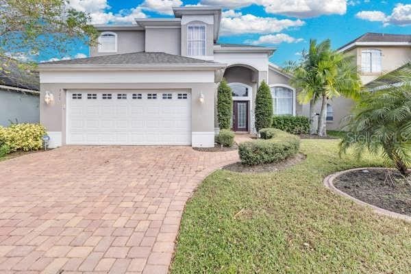 721 Hardwood Cir, Orlando, FL 32828 - view of front facade with stucco siding, decorative driveway, a garage, and a front lawn
