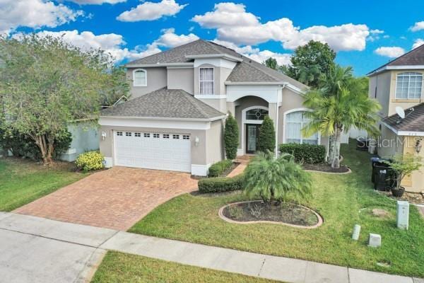 721 Hardwood Cir, Orlando, FL 32828 - view of front of house featuring decorative driveway, stucco siding, a garage, a front yard, and a shingled roof