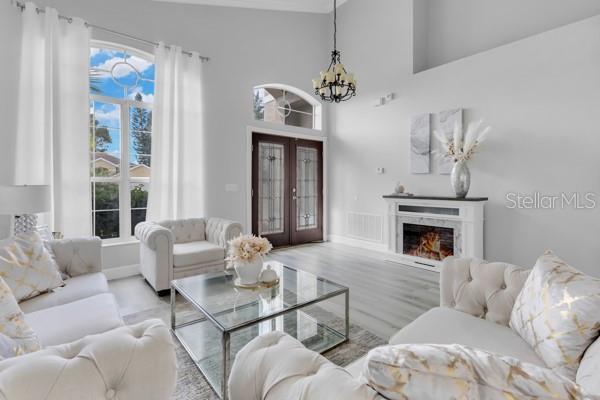 721 Hardwood Cir, Orlando, FL 32828 - living area with a chandelier, wood finished floors, a lit fireplace, french doors, and baseboards