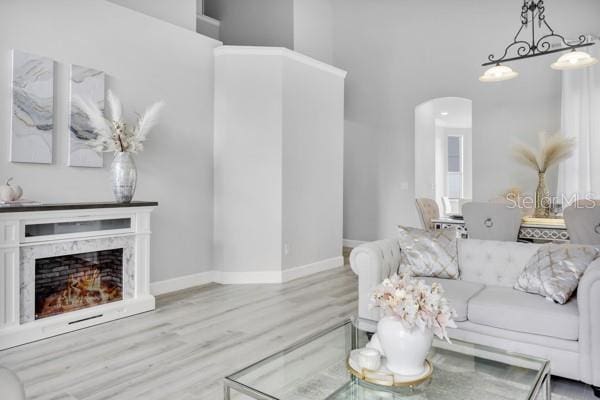 721 Hardwood Cir, Orlando, FL 32828 - living room featuring arched walkways, wood finished floors, a high ceiling, baseboards, and a fireplace