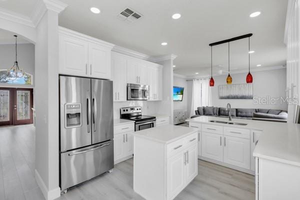 721 Hardwood Cir, Orlando, FL 32828 - kitchen with stainless steel appliances, a sink, light countertops, white cabinetry, and ornamental molding