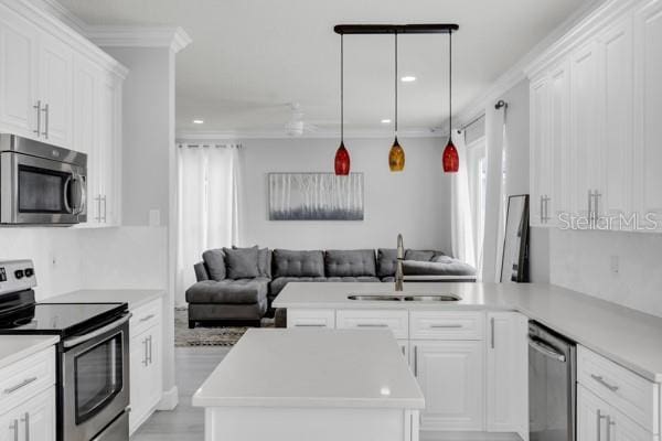 721 Hardwood Cir, Orlando, FL 32828 - kitchen featuring appliances with stainless steel finishes, a sink, open floor plan, white cabinets, and recessed lighting