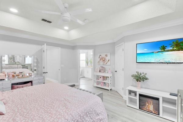 721 Hardwood Cir, Orlando, FL 32828 - bedroom featuring a tray ceiling, wood finished floors, baseboards, connected bathroom, and recessed lighting