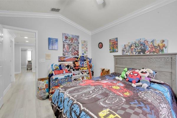 721 Hardwood Cir, Orlando, FL 32828 - bedroom with wood finished floors, vaulted ceiling, crown molding, a ceiling fan, and baseboards