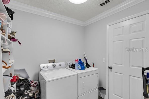 721 Hardwood Cir, Orlando, FL 32828 - washroom with washing machine and dryer, ornamental molding, and a textured ceiling