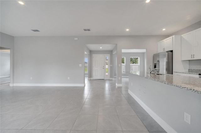 502 Viceroy Ct, Kissimmee, FL 34758 - kitchen featuring stainless steel fridge with ice dispenser, open floor plan, light stone counters, white cabinets, and baseboards