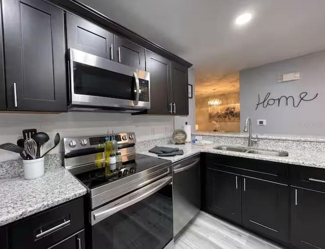 2798 Club Cortile Cir Unit A, Kissimmee, FL 34746 - kitchen with stainless steel appliances, a sink, dark cabinetry, light stone countertops, and recessed lighting