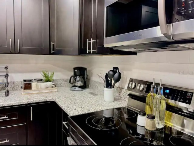 2798 Club Cortile Cir Unit A, Kissimmee, FL 34746 - kitchen featuring stainless steel appliances, light stone counters, and dark brown cabinetry