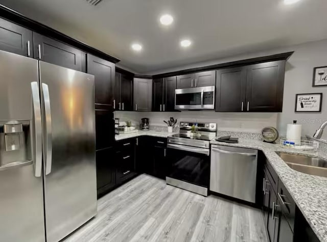 2798 Club Cortile Cir Unit A, Kissimmee, FL 34746 - kitchen featuring stainless steel appliances, a sink, light stone counters, recessed lighting, and light wood-style flooring