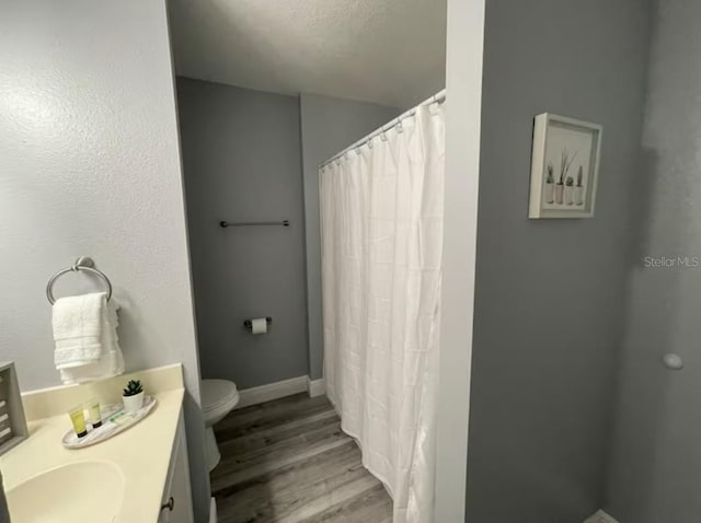 2798 Club Cortile Cir Unit A, Kissimmee, FL 34746 - full bath featuring wood finished floors, toilet, vanity, a shower with shower curtain, and baseboards