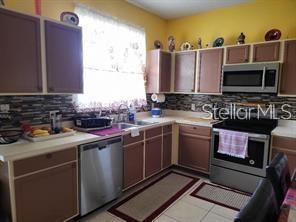 1107 Dartford Dr, Kissimmee, FL 34758 - kitchen with stainless steel appliances, decorative backsplash, light countertops, a sink, and light tile patterned floors